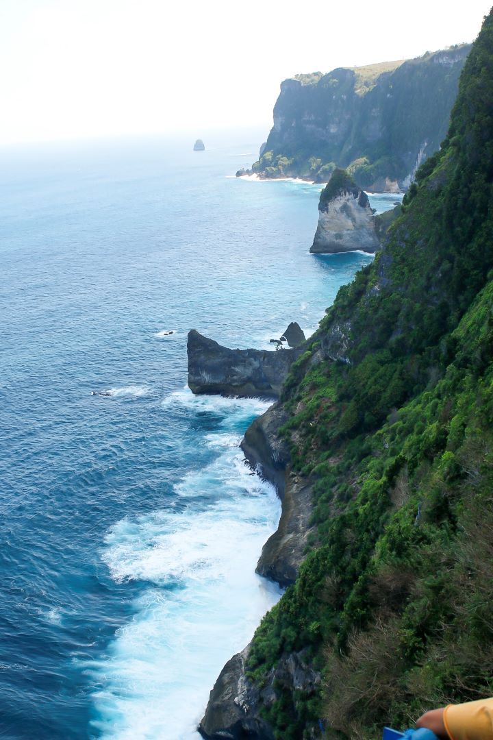 ruta por indonesia vistas acantilado con montañas llena de vegetacion y olas rompiendo